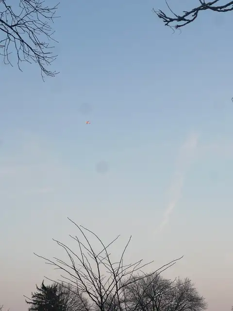 A small orange spark in the cool, wide open sky.